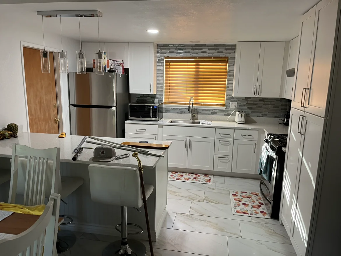 Renovated kitchen with white cabinetry and pendant lights